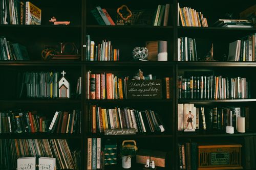 Free A warm display of a vintage bookshelf filled with books, candles, and home decor items. Stock Photo