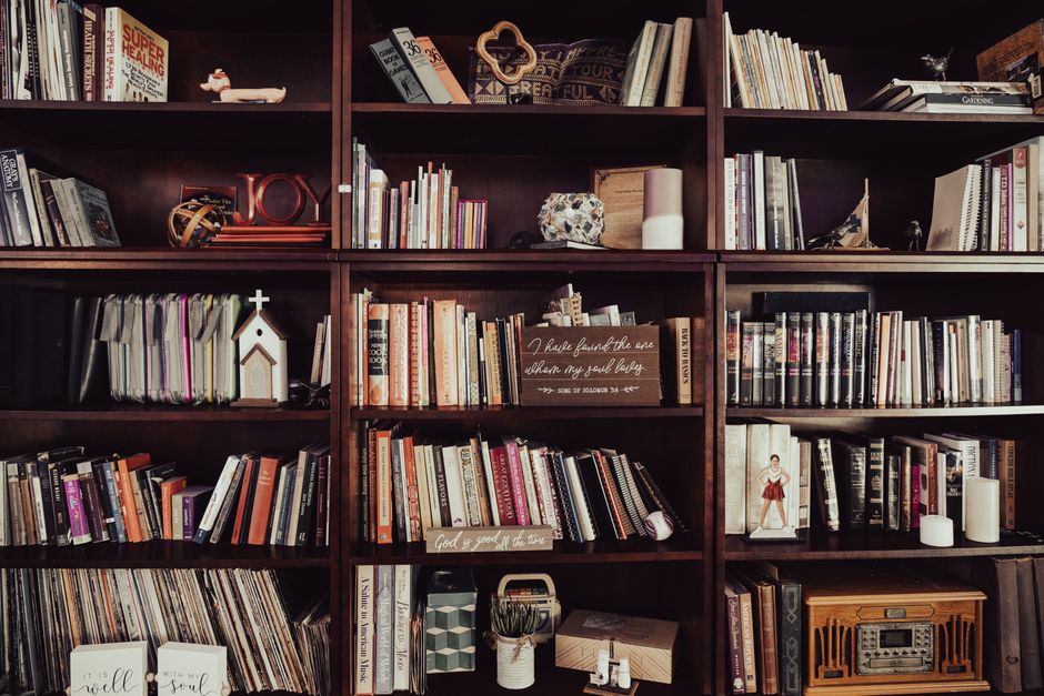 Warm-toned bookshelf filled with diverse books, religious decor, and trinkets.