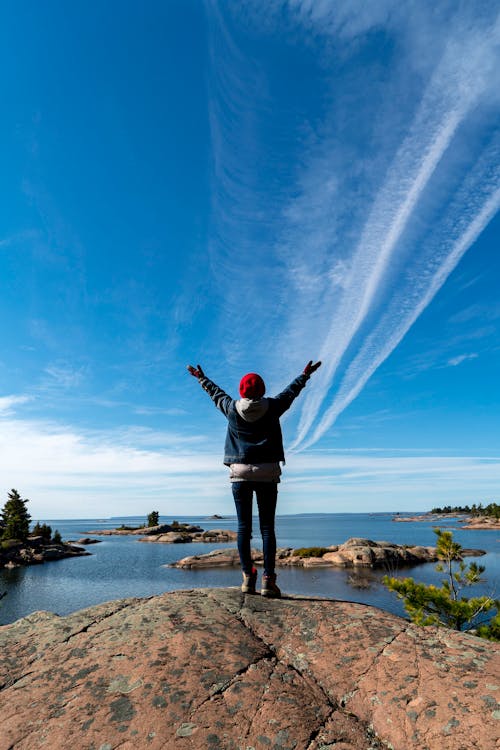 Back View of a Person Standing on the Rock under the Blue Sky