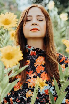 A red-haired woman in a floral dress enjoys the tranquility among blooming sunflowers.