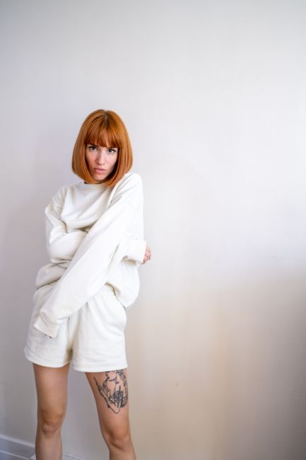 Fashionable woman with red bob haircut posing indoors in casual outfit.
