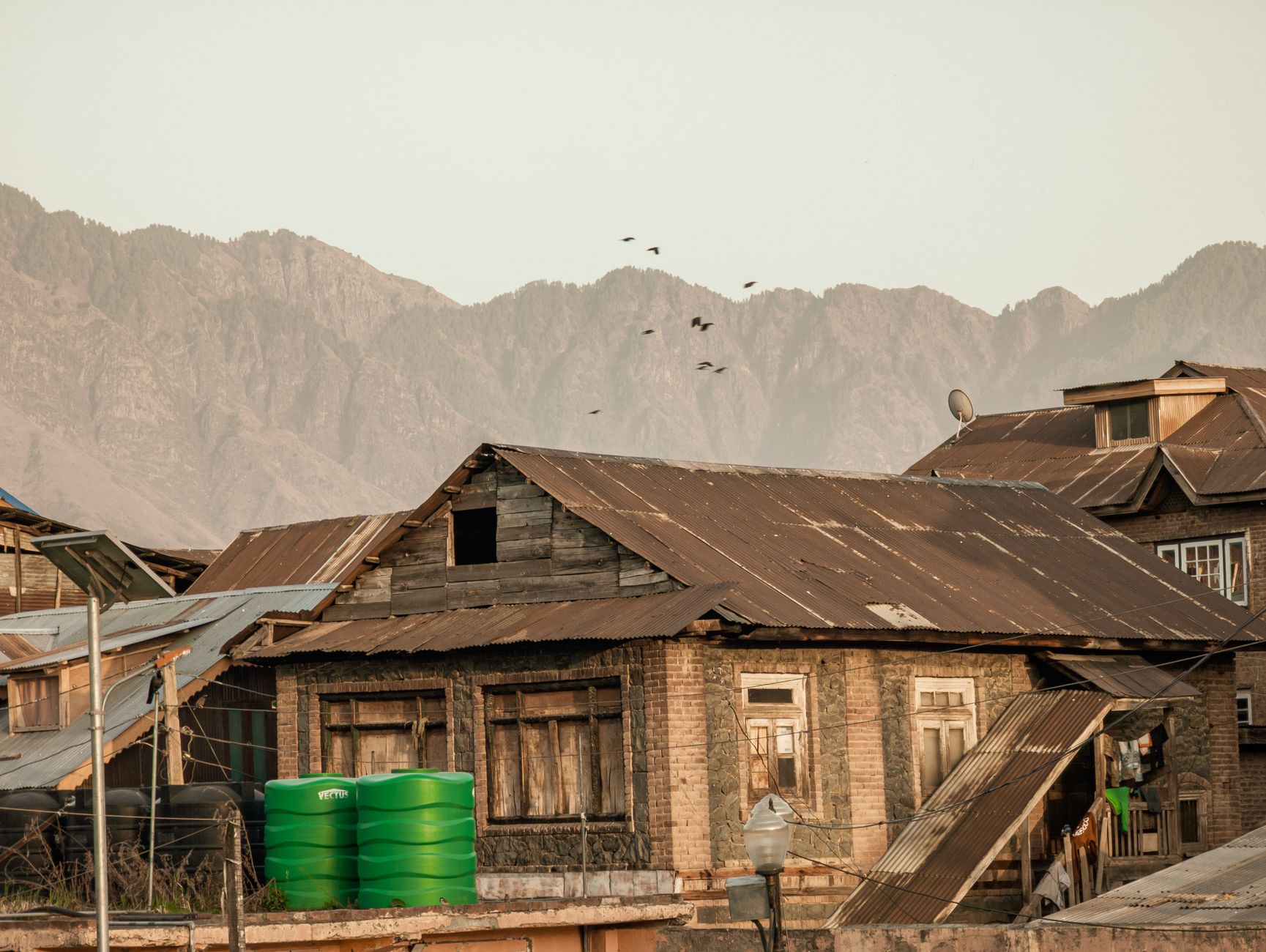 Charming old village houses in Srinagar with majestic mountain backdrop captured during daytime.