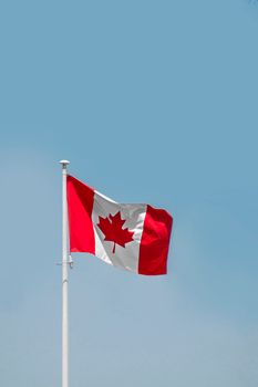 A waving Canadian flag set against a clear blue sky, symbolizing national pride in Ottawa.