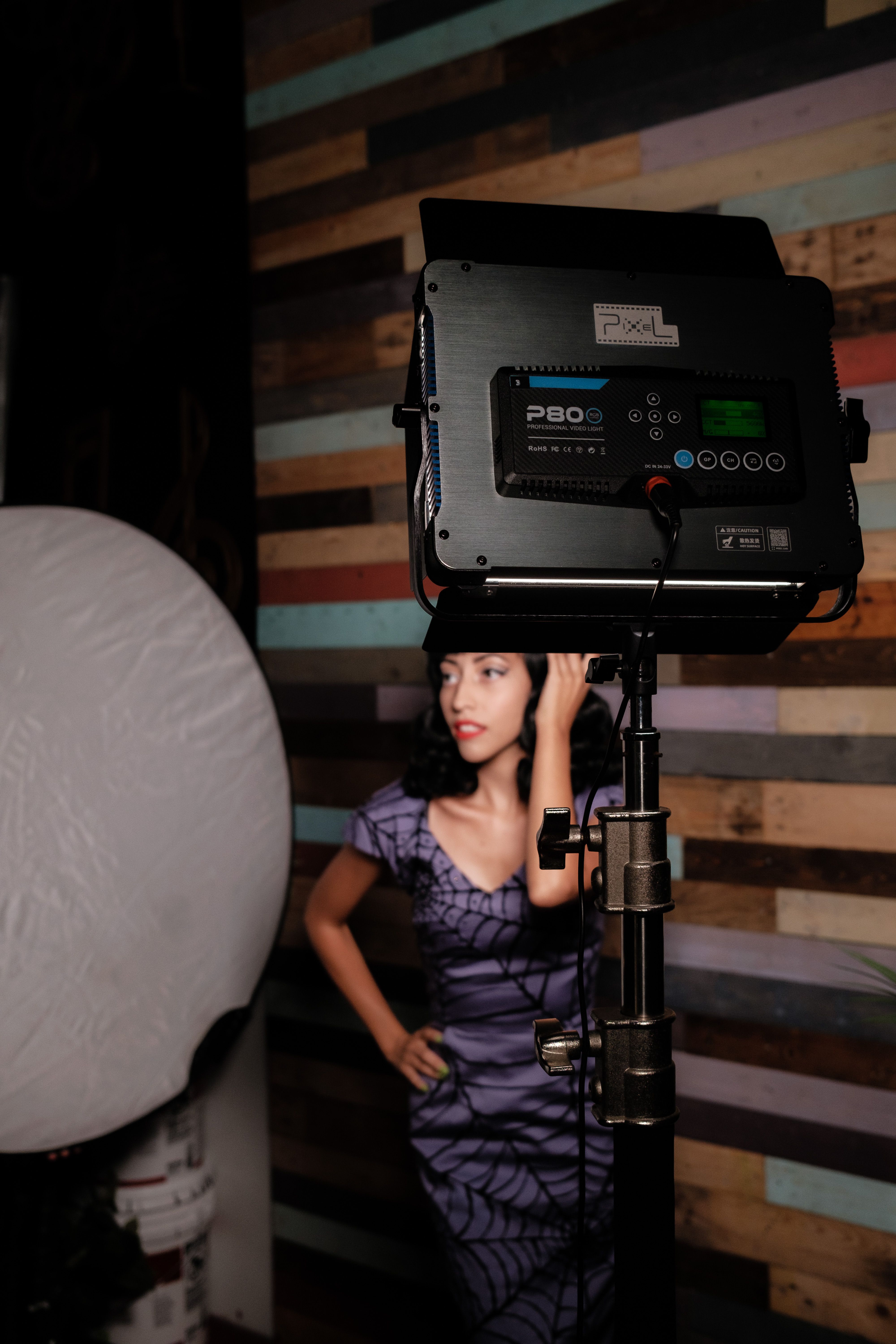 Stock photo: A woman in a studio poses near professional lighting equipment, striking a confident pose