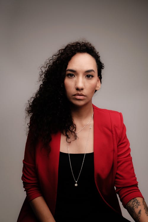 A Woman in Red Blazer Wearing Silver Necklace while Looking with a Serious Face