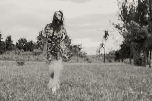 Grayscale Photo of a Woman Running on a Grass Field