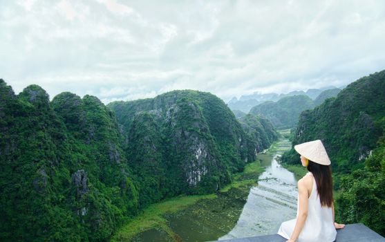 A woman in a traditional hat enjoys the stunning river and valley view, perfect for travel themes.