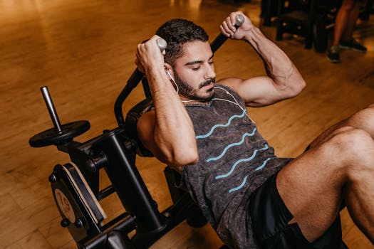 An adult man working out indoors on gym equipment, building muscle and strength.