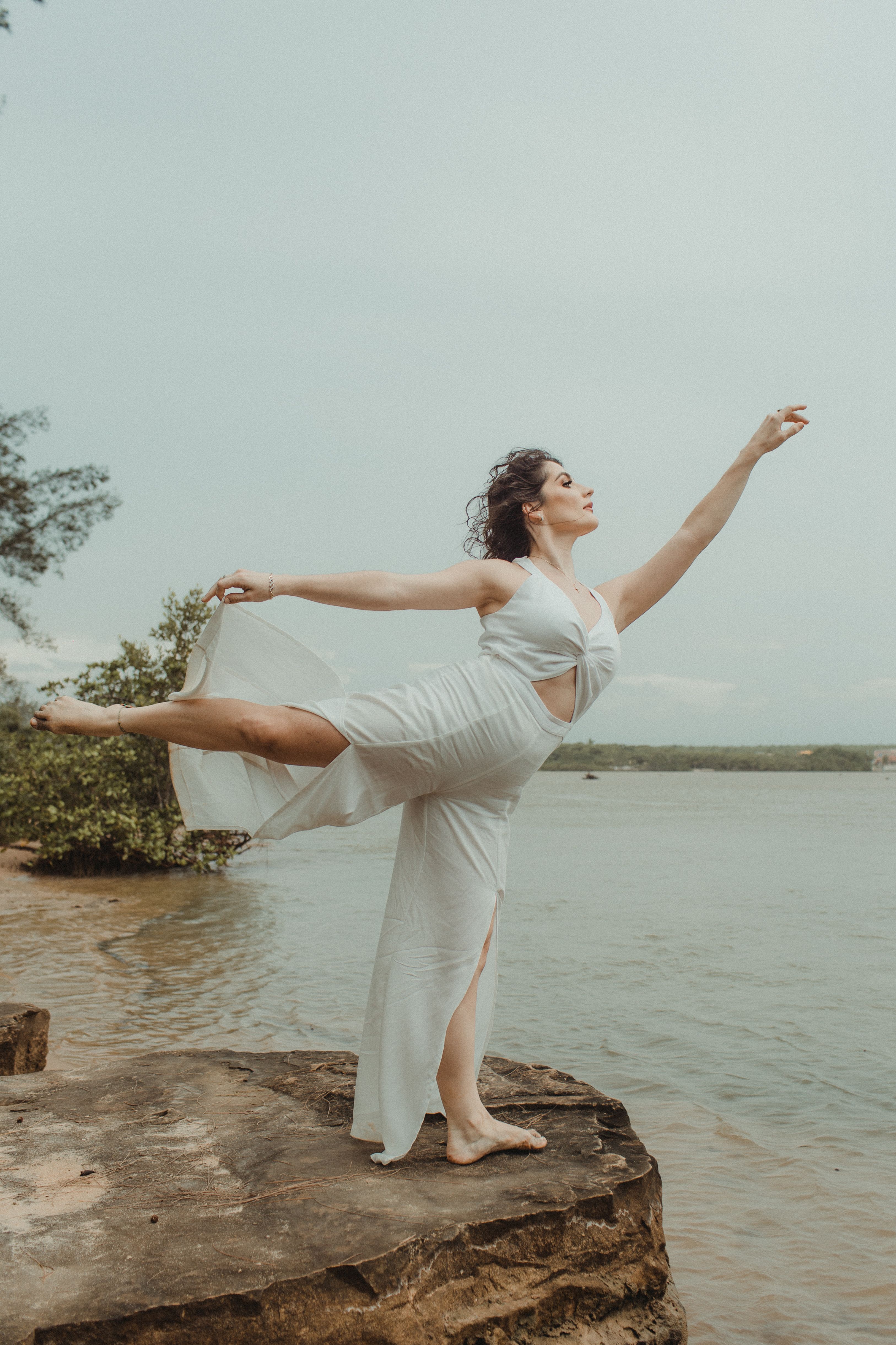 A Woman in White Pants Standing Barefooted on a Rock Formation · Free ...
