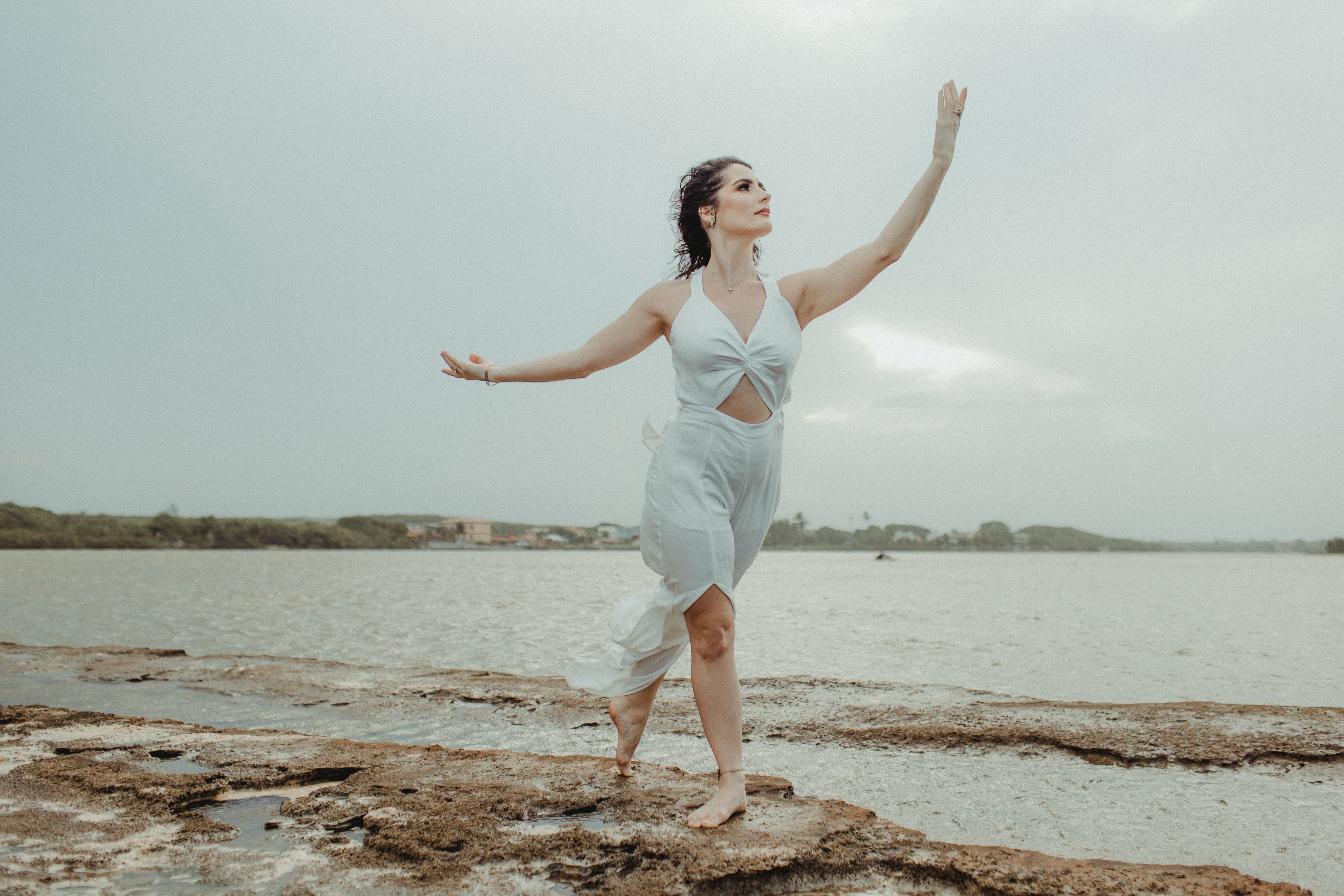 Woman in White Dress Standing on Brown Rock Near Body of Water · Free ...