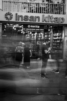 Blurred motion of people outside a bookstore at night. Black and white image.