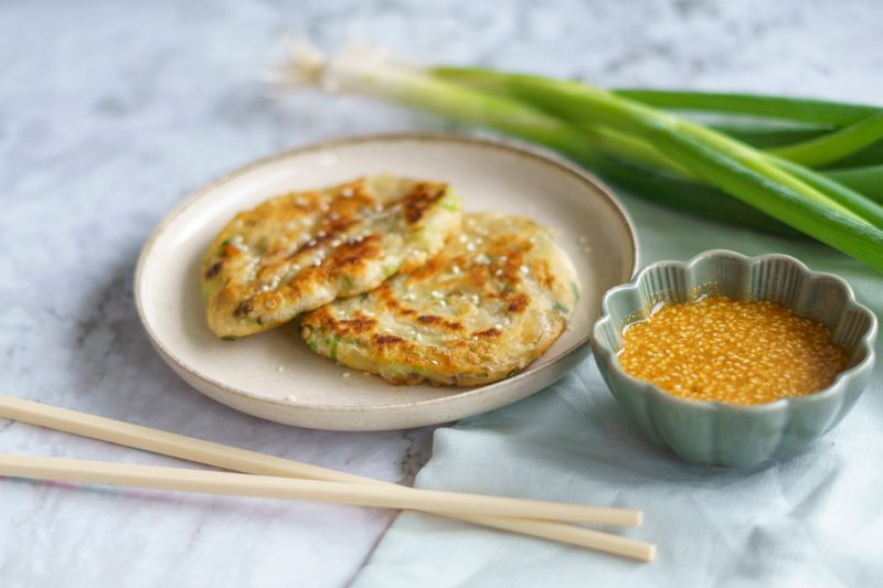 Crispy Korean scallion pancake cut into wedges, served with a sesame dipping sauce