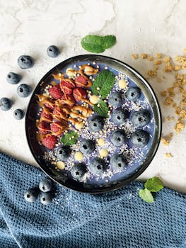 Top view of a nutritious smoothie bowl topped with fresh berries and granola.