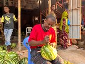 A vendor skillfully slices watermelon at an outdoor market in Mogadishu, Somalia.