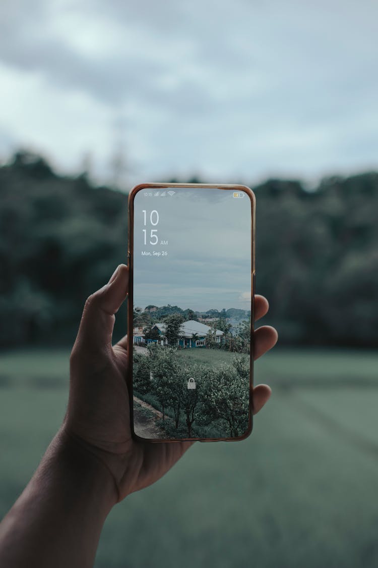 Hand Holding Cellphone With Rural Photo Wallpaper