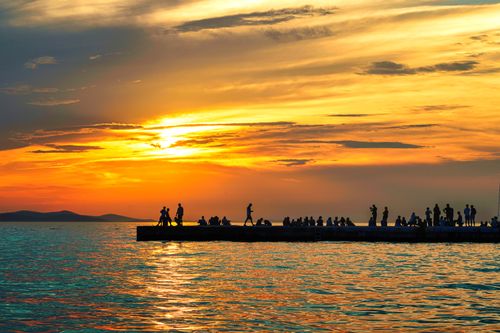 Free A vibrant sunset with silhouettes of people on a pier in Zadar, Croatia. Stock Photo