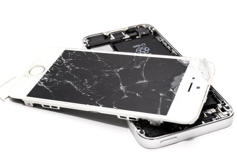 Close-up of a broken smartphone with a severely cracked screen.