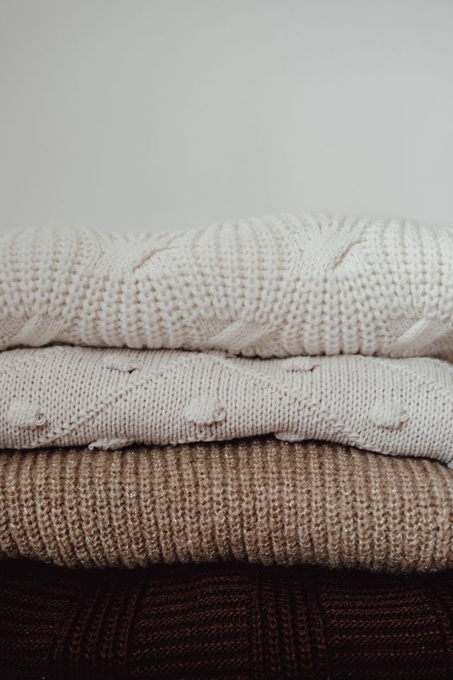 Vertical stack of knitted sweaters in neutral tones, photo by Büşra İnce on Pexels