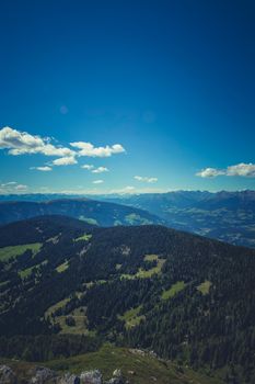 Scenic view of a lush mountain range under a bright blue sky with scattered clouds.
