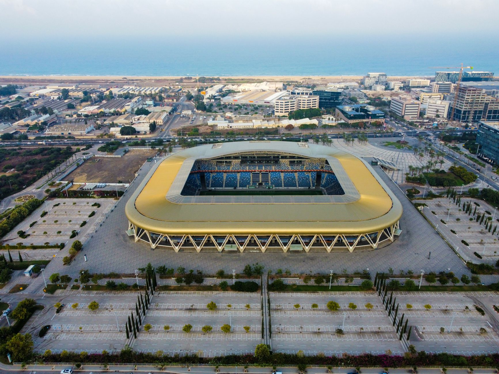 Aerial shot of a modern stadium near the coast with parking area.