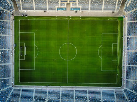 Drone shot capturing a top-down view of a vacant soccer stadium with a well-marked green field.