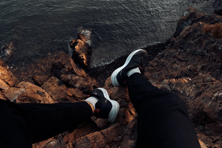 Legs In Running Shoes Hanging Over Cliff Edge