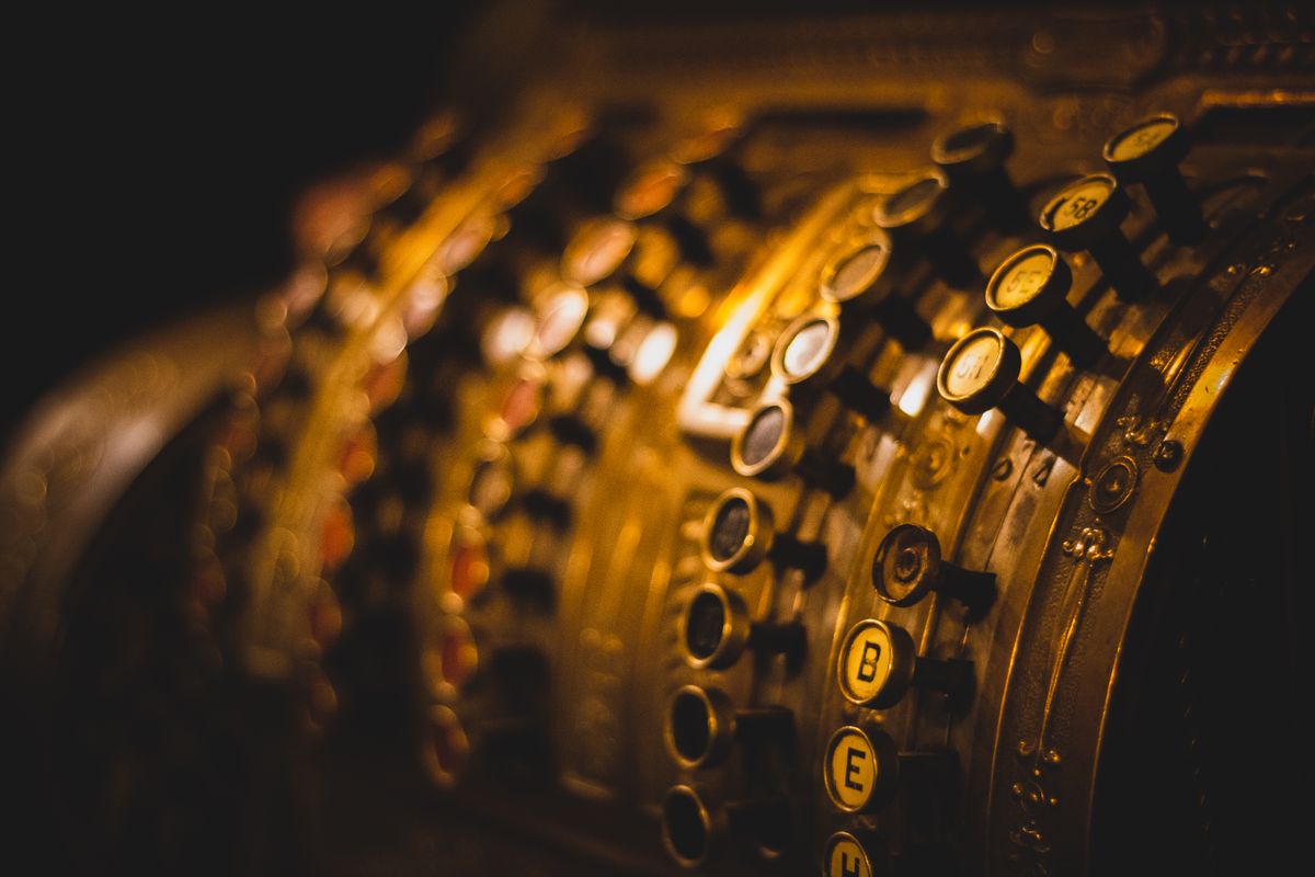 Close-up of an antique cash register with golden tones, showcasing retro details and reflections.
