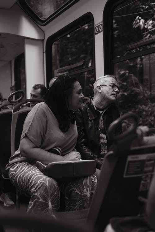 Grayscale Photo of a Couple Sitting inside a Train