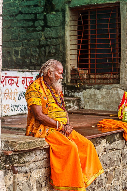 Indian Man in Traditional Clothing Sitting on a Wall 