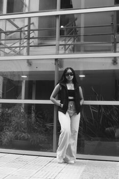 Black and white photo of a fashionable woman posing confidently outdoors.