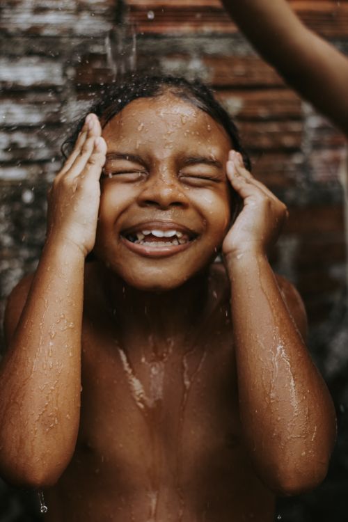 Free A young child enjoys a refreshing outdoor shower, embracing the water with joy. Stock Photo
