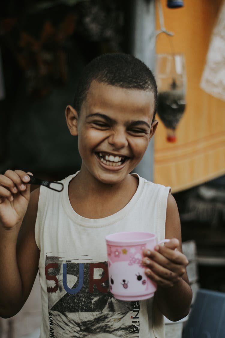 Boy Laughing While Holding A Pink Cup