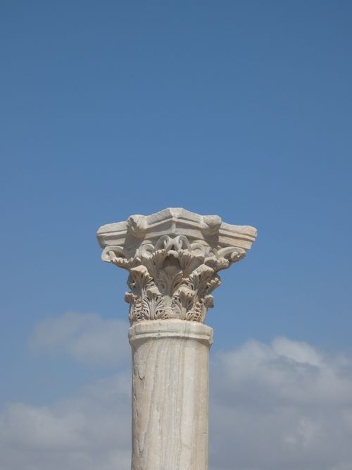 Free A detailed view of an ancient ornate column with a clear blue sky backdrop. Stock Photo