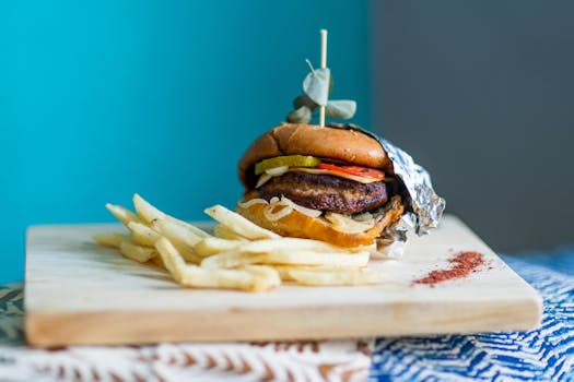 Delicious hamburger with crispy fries on a wooden surface, ready to enjoy.