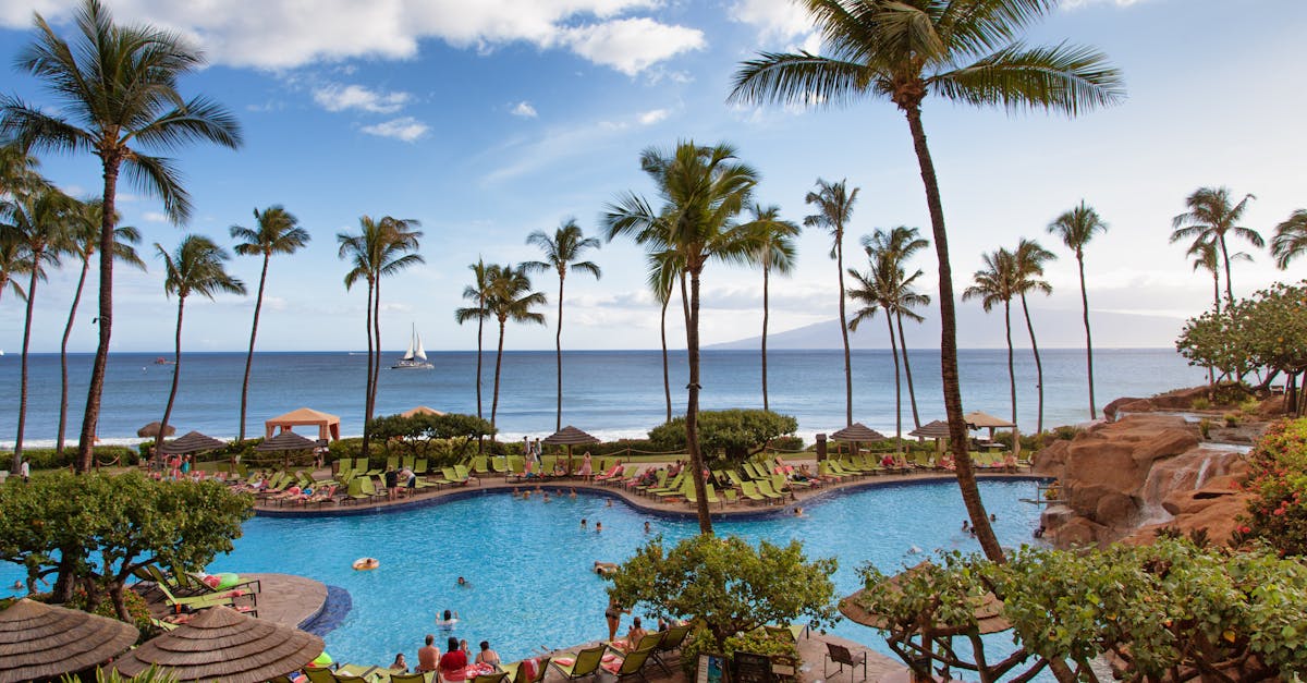 Photo by Lindsey Garrett Stunning view of a tropical beach resort with palm trees and a pool in Kaanapali, Hawaii.