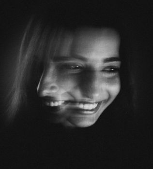 A creative black and white portrait featuring a long exposure effect of a smiling woman.
