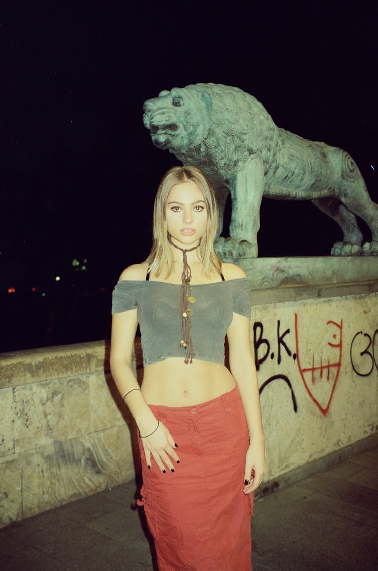 Portrait Of A Beautiful Blonde Posing In Front Of A Lion Statue At Night