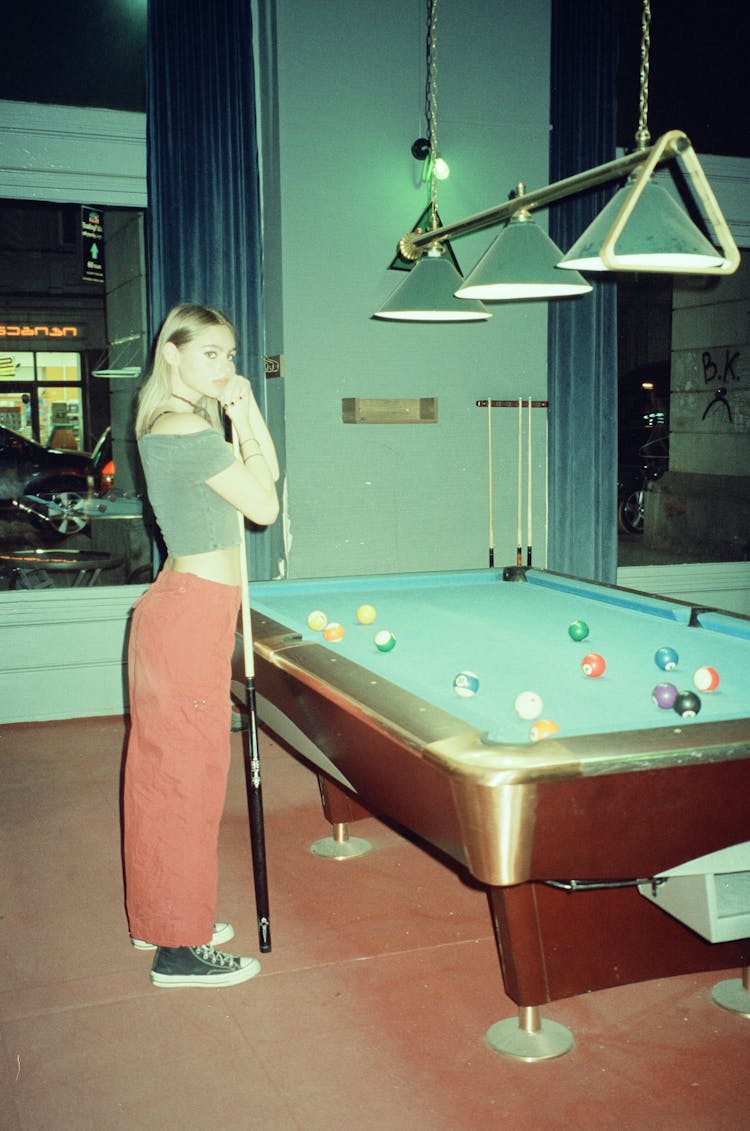 Pretty Blonde Standing In Front Of A Pool Table