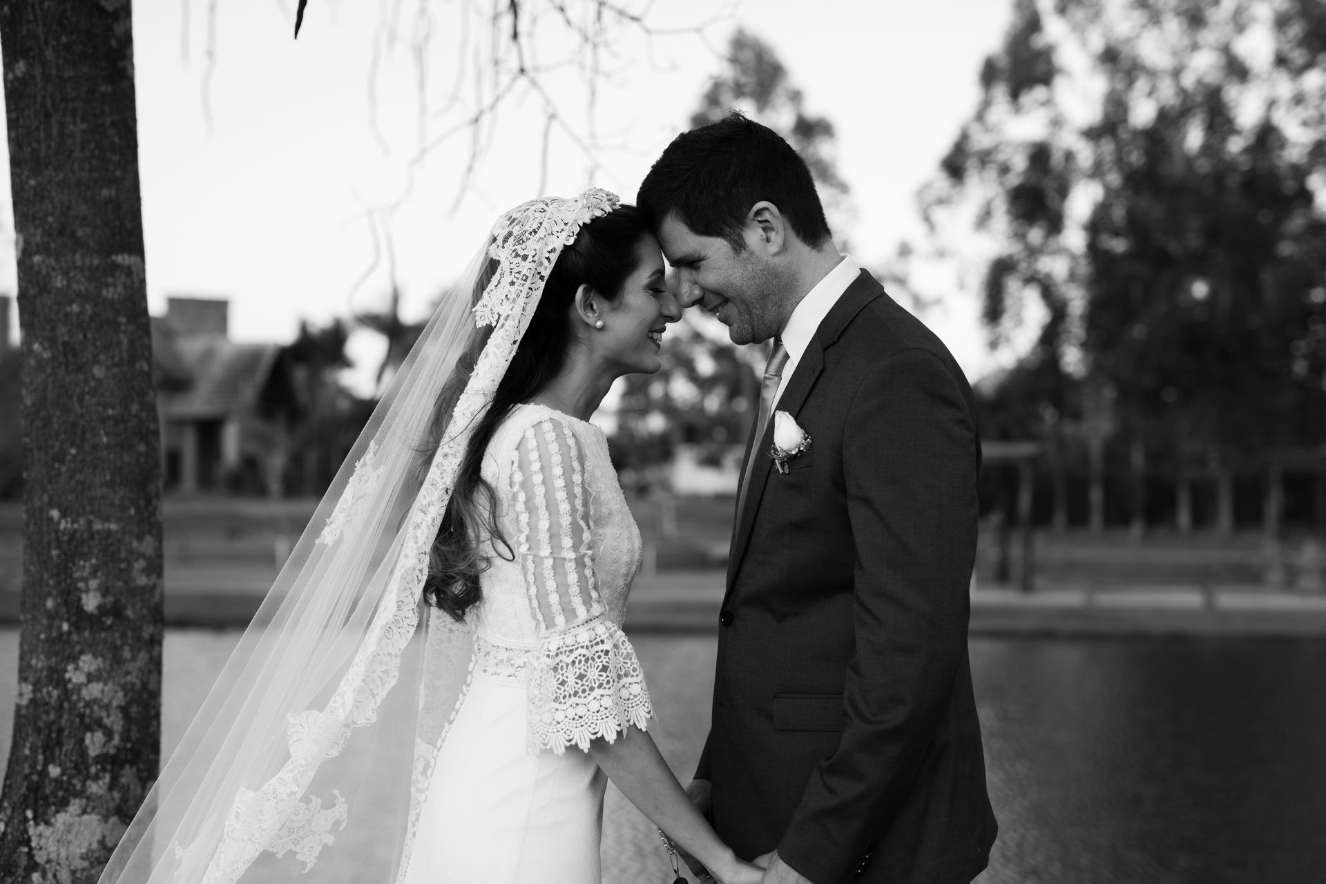 Bride and groom embracing by a lake on their wedding day