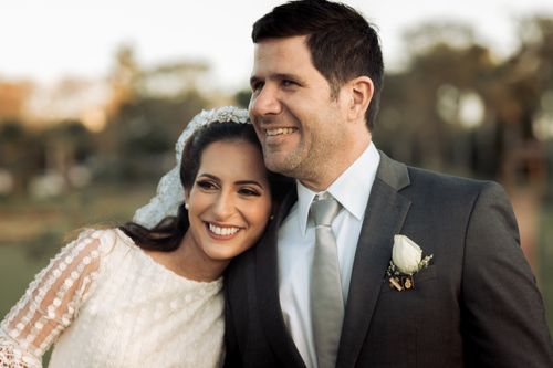 Free Charming outdoor wedding portrait capturing the joy of a newlywed couple embracing with smiles. Stock Photo