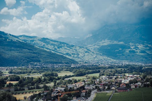 An Aerial Photography of City Near the Mountains Under the Cloudy Sky