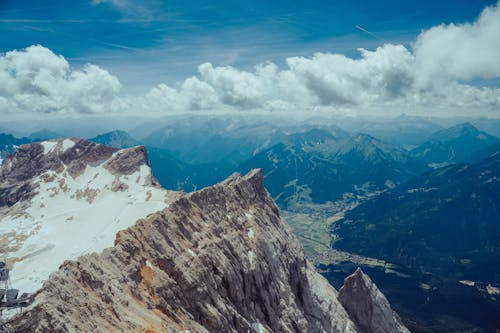 An Aerial Photography of a Snow Covered Mountains Under the Cloudy Sky