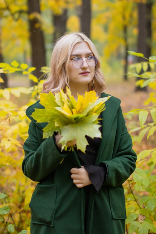 Woman in Green Coat Holding Autumn Leaves