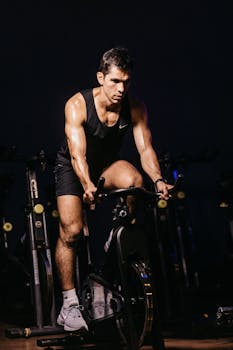 A determined male athlete engaged in an intense indoor cycling session. Perfect for fitness-themed designs.