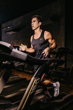 Focused man running on a treadmill in a gym, showcasing athleticism and fitness.