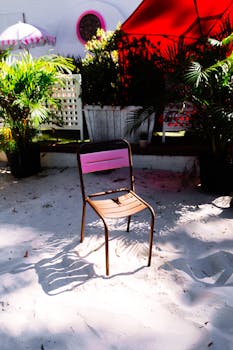 Brightly colored chair on sandy ground surrounded by lush palm plants in Atlanta outdoor setting.