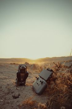 Drone with controller on arid ground at sunset, capturing the essence of modern technology in nature.