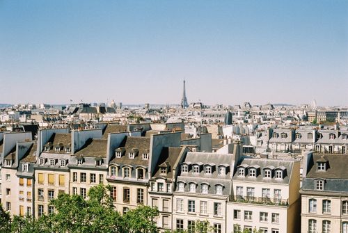 Free A scenic aerial view of Paris rooftops with the Eiffel Tower in the background under a clear blue sky. Stock Photo