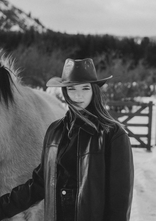 Free Portrait of a woman in a cowboy hat with a horse in a snowy landscape. Stock Photo