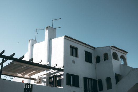 White residence with arched windows and antennas under a clear sky.